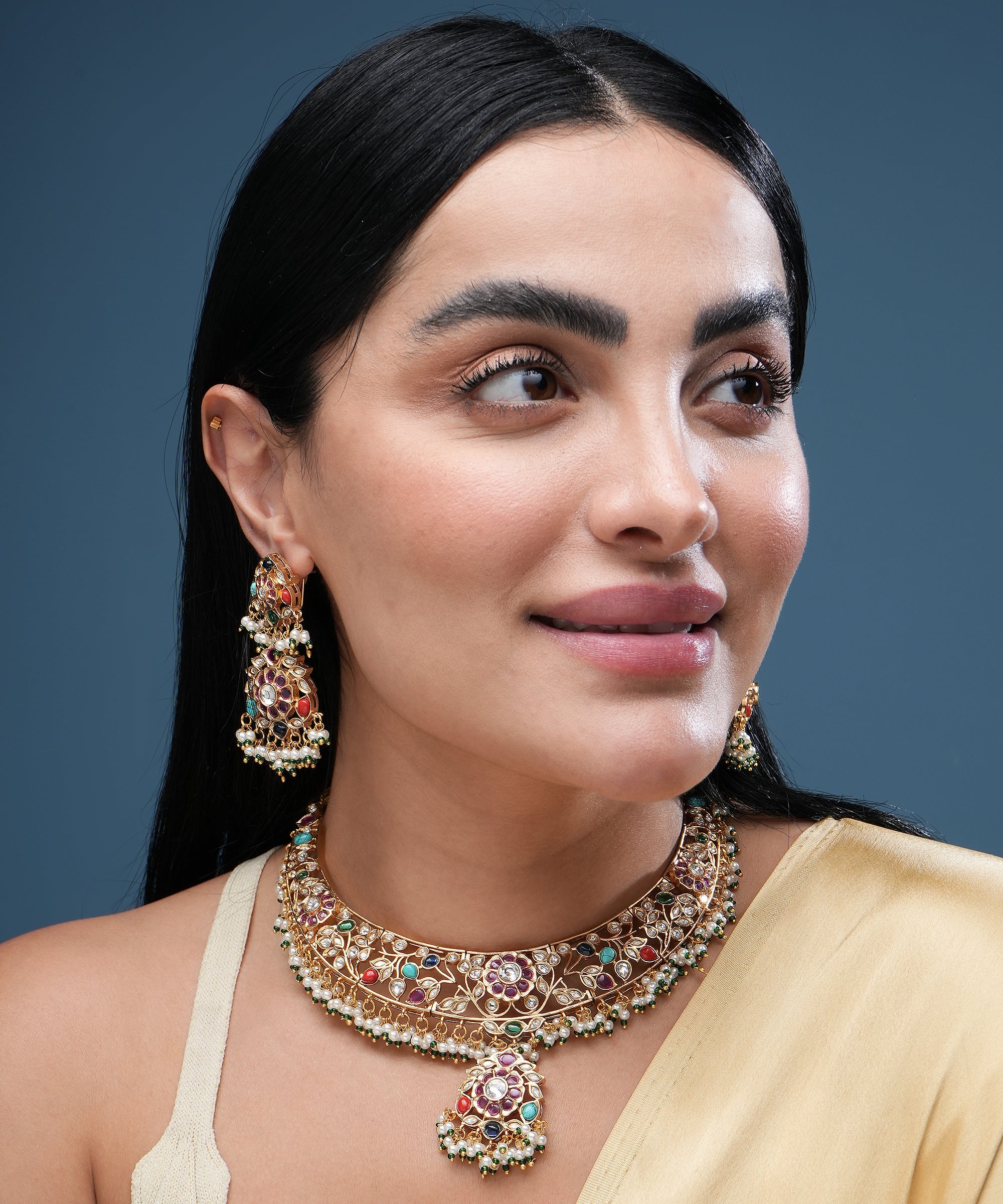 Woman wearing traditional multicolor kundan choker necklace set with matching earrings and pearl bead detailing.