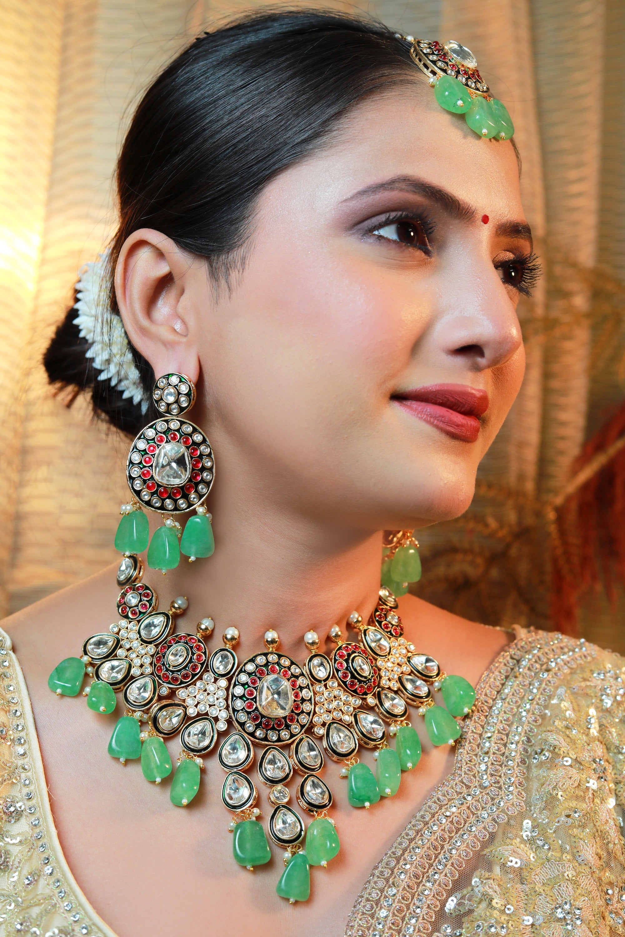 “Bridal Kundan necklace set with white stones, ruby accents, and emerald-green bead drops including matching earrings and maang-tikka.”