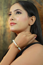 Woman wearing white pearl necklace and matching bracelet with gold accent bead.