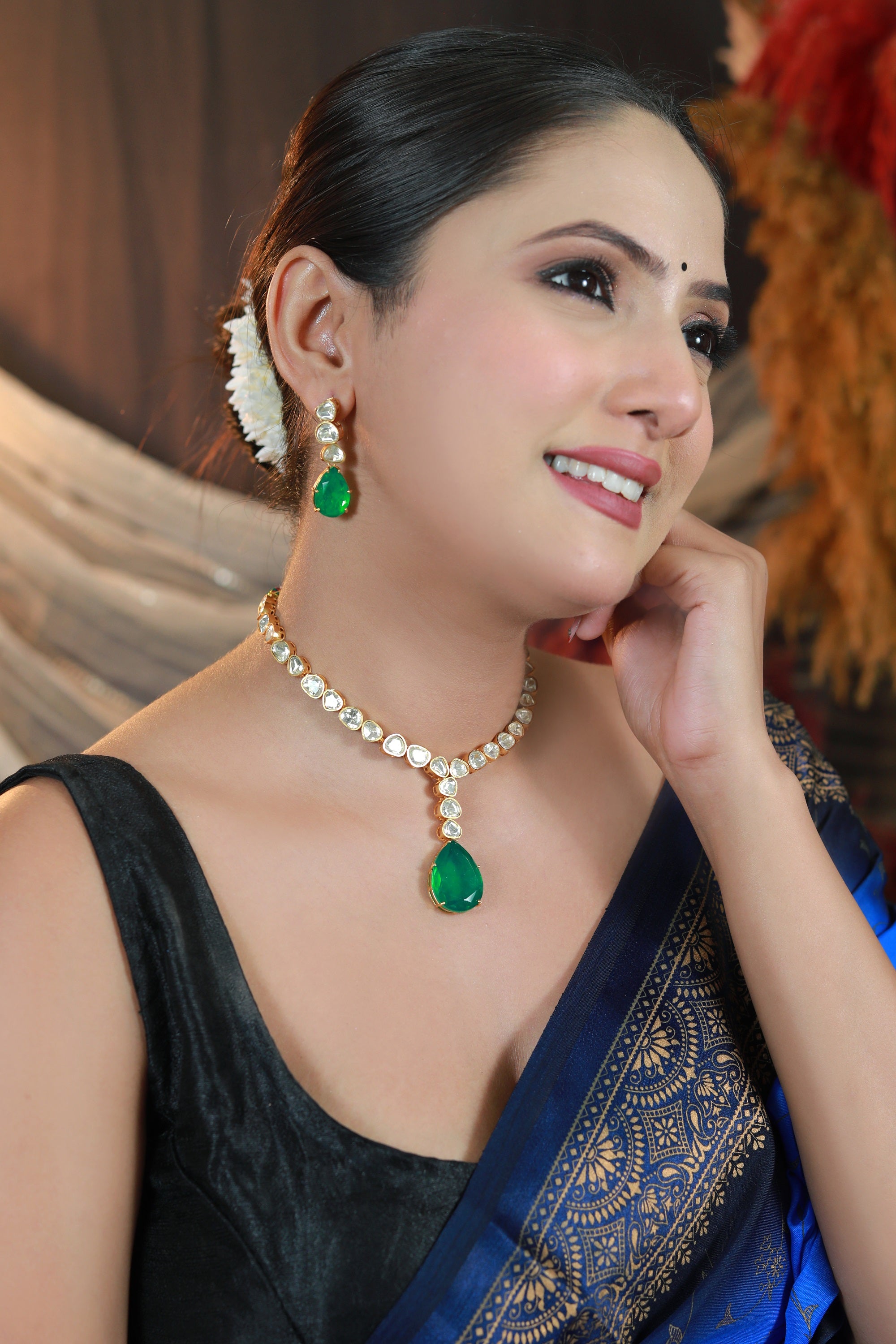“Close-up of green stone kundan earring with gold-tone detailing — Damani Jewels.”