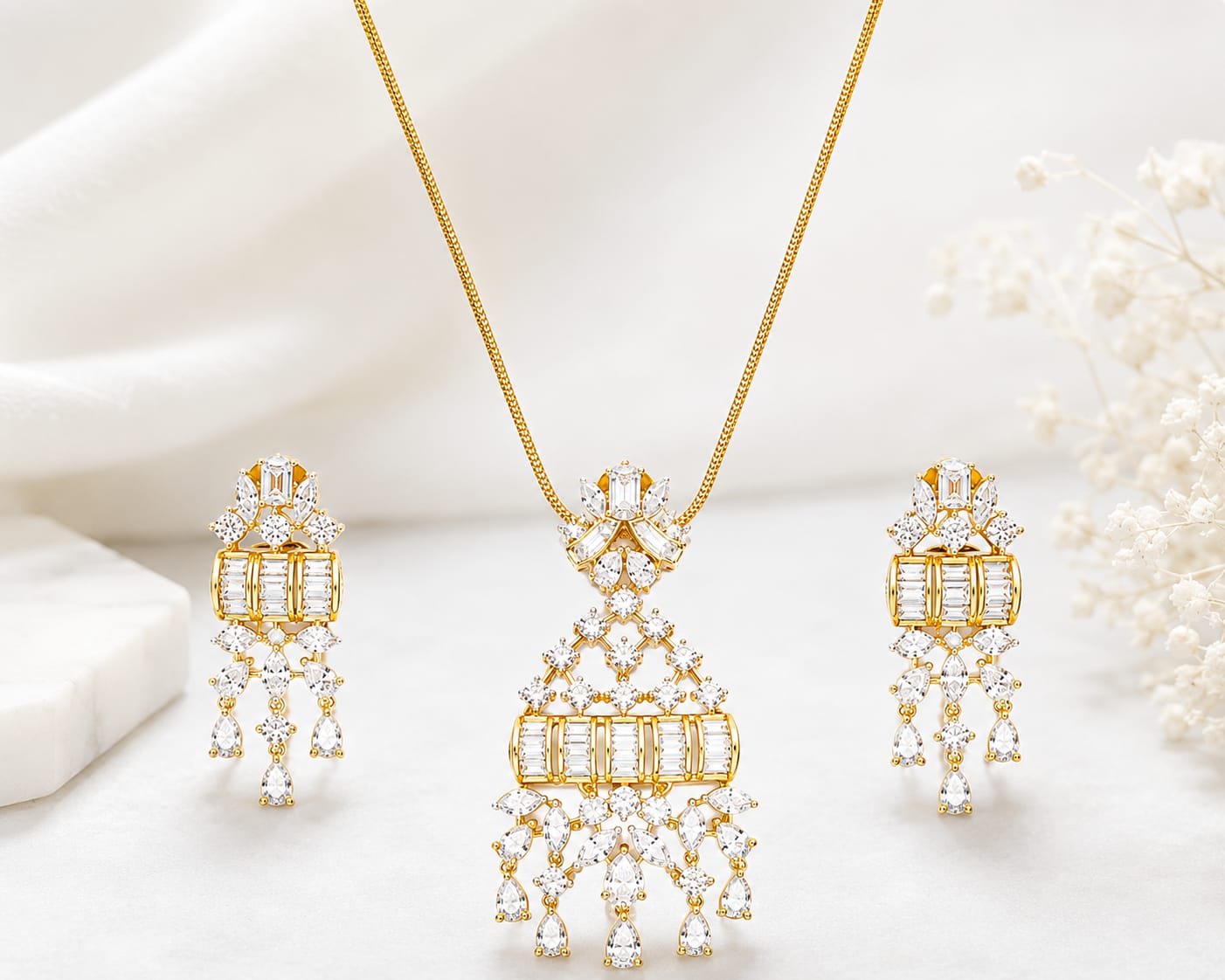 Luxury gold-tone crystal pendant necklace with matching chandelier drop earrings featuring baguette and pear-cut stones for bridal and party wear.