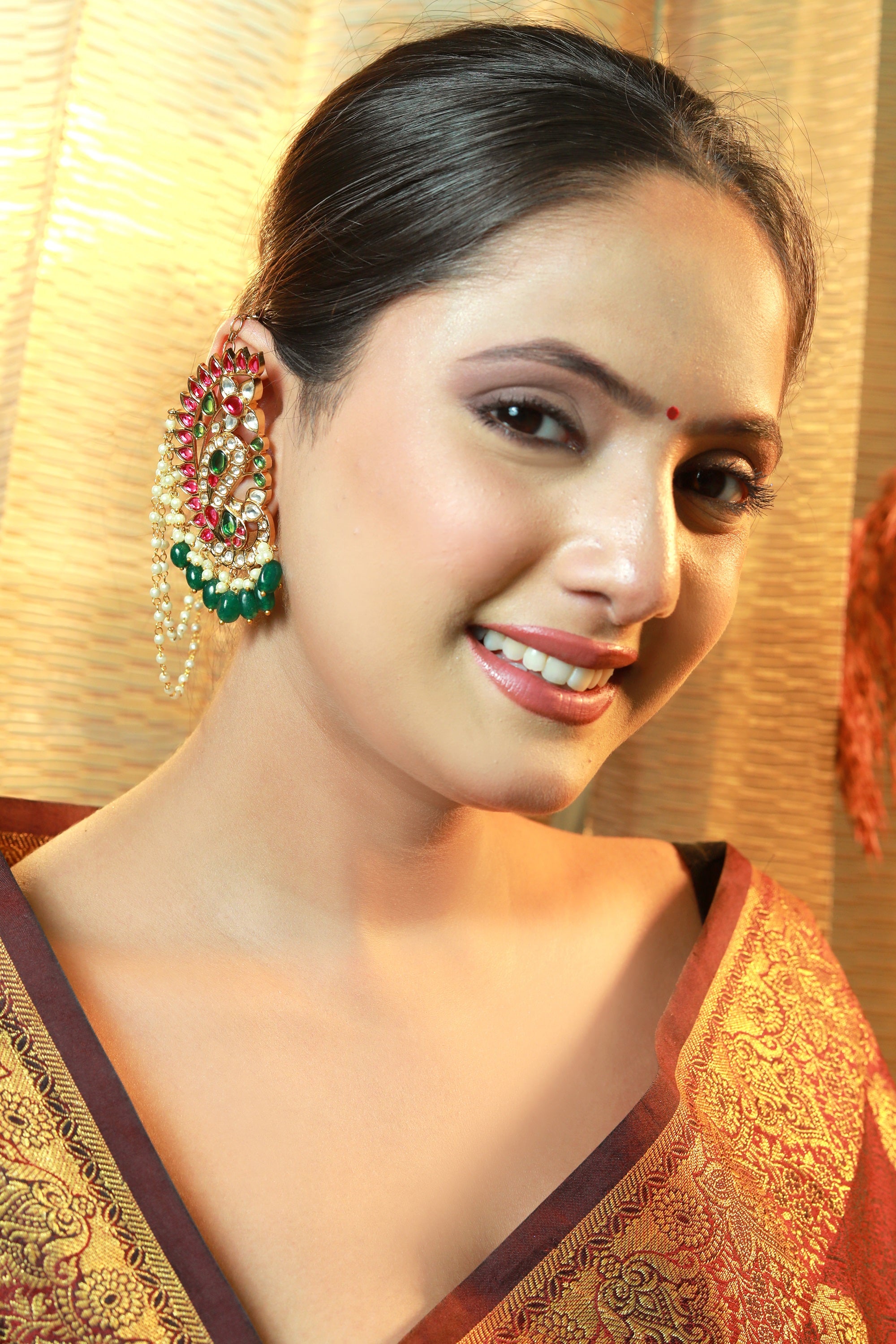 Bridal ear chain earring with pearls, red and green kundan stones — worn with traditional bun hairstyle
