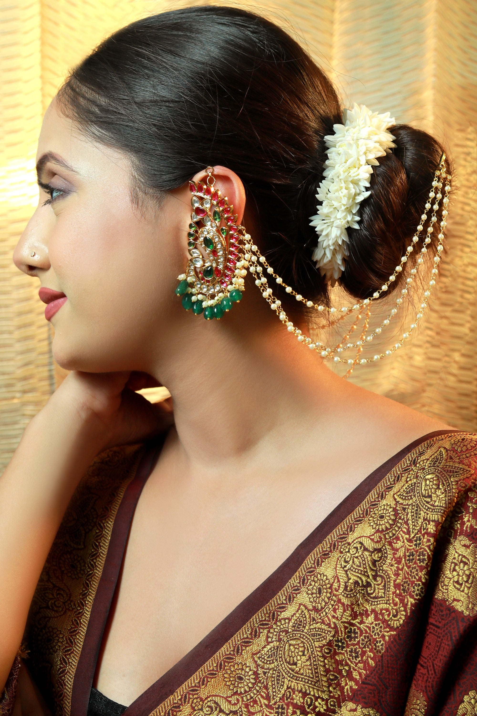 Bridal ear chain earring with pearls, red and green kundan stones — worn with traditional bun hairstyle