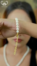 Woman wearing white pearl necklace and matching bracelet with gold accent bead.